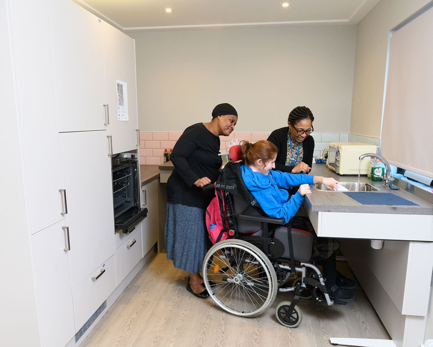 A support worker and a young adult cooking together at home